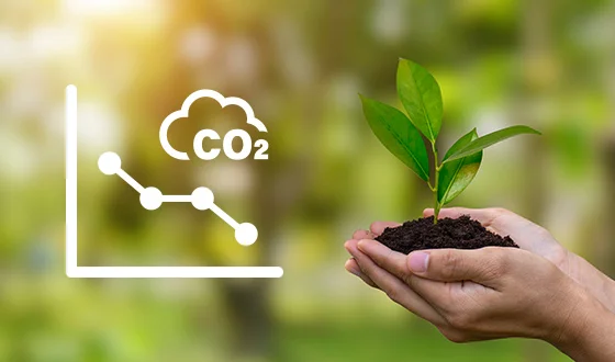 CO₂排出量の低下を示すグラフと、環境に配慮した取り組みを象徴する若葉と手の画像