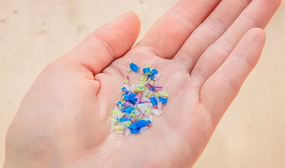 プラスチック材料の再資源化を示す手とプラスチック片の画像